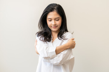 Smiling positive, hugging oneself happy asian young woman hands hug herself shoulders enjoy joyful, self hugging, self love and self care, face expression self esteem standing isolated on background. - obrazy, fototapety, plakaty