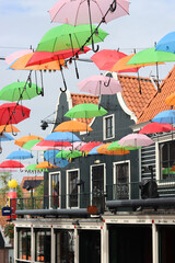 Fototapeta na wymiar Colorful umbrellas on the street of Volendam city, the Netherlands. Sunny day in Europe. Summer vacation concept. 
