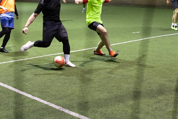 Futsal soccer football players with ball on artificial grass indoors. Space fort copy.