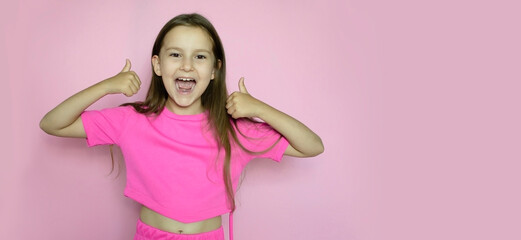 Charming schoolgirl in pink suit raises her fingers up in gesture on a pink background