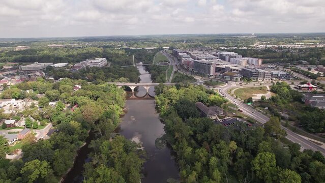 Aerial drone establishing view of Bridge Park businesses, roadway traffic, new restaurants, and hotels by the Scioto River in rich upper-class downtown Dublin, OH northwest of Columbus, Ohio
