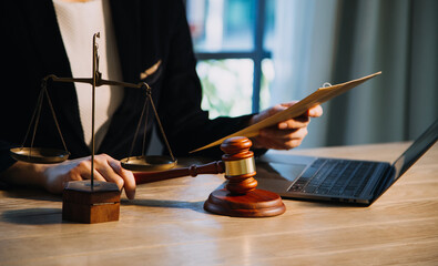 Justice and law concept.Male judge in a courtroom with the gavel, working with, computer and docking keyboard, eyeglasses, on table in morning light