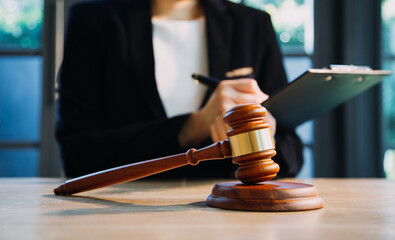 Justice and law concept.Male judge in a courtroom with the gavel, working with, computer and docking keyboard, eyeglasses, on table in morning light