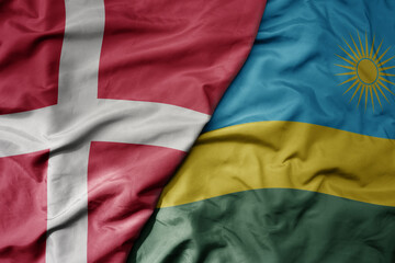 big waving national colorful flag of denmark and national flag of rwanda .