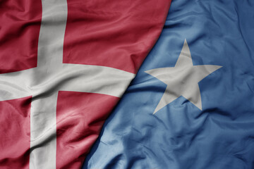 big waving national colorful flag of denmark and national flag of somalia .