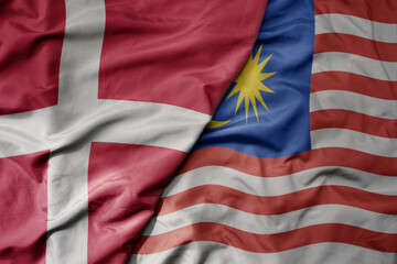 big waving national colorful flag of denmark and national flag of malaysia .