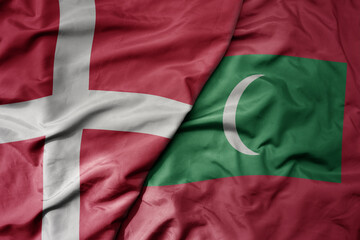 big waving national colorful flag of denmark and national flag of maldives .