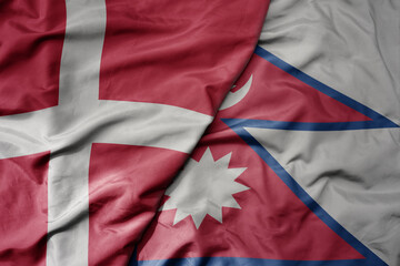 big waving national colorful flag of denmark and national flag of nepal .