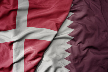 big waving national colorful flag of denmark and national flag of qatar .