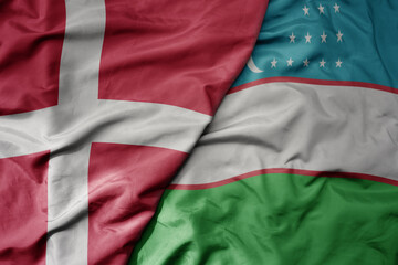 big waving national colorful flag of denmark and national flag of uzbekistan .
