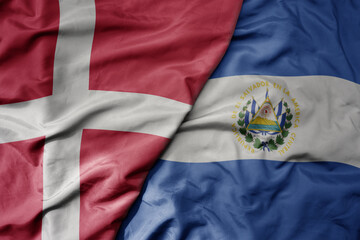 big waving national colorful flag of denmark and national flag of el salvador .