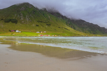 Morning View from Refviksanden Beach Near Maloy: Turquoise Sea, Rustic Houses, and Cloud-Capped Mountain