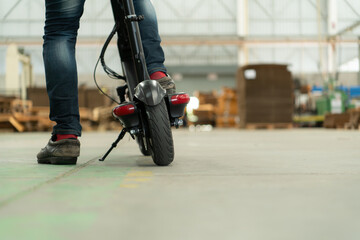 An electric scooter is parked in a large factory warehouse. It is necessary for the convenience of the factory manager.