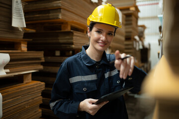 A young female warehouse worker checks and counting cardboard boxes in the warehouse using a digital tablet.