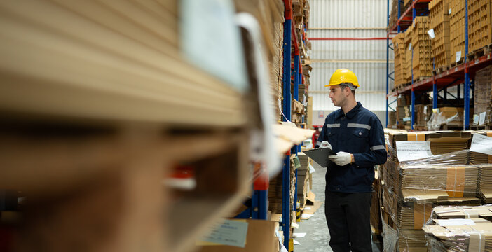 Young male warehouse worker checking stock in a warehouse. This is a large paper package storage and distribution warehouse.