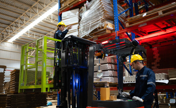 Warehouse workers using forklift to check and counting in a large warehouse. This is a large paper package storage and distribution warehouse.