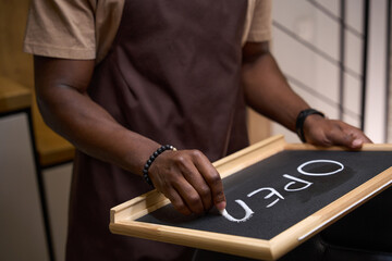 Young man writes in chalk on a sign open