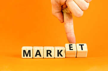 Mark of market symbol. Businessman turns wooden cubes and changes word Mark to Market. Beautiful orange table orange background. Business mark of market concept. Copy space.