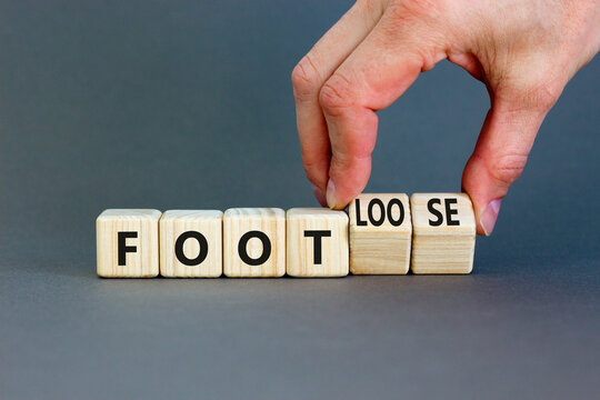 Naklejki Foot or footloose symbol. Businessman turns wooden cubes and changes word Foot bad to Footloose. Beautiful grey table grey background. Business foot or footloose concept. Copy space.