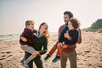 Young happy family walking on a sandy beach during winter