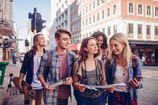 Young and diverse group of tourists exploring and using a map in the city while traveling on their vacation