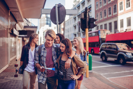 Young and diverse group of friends exploring and using the map in the city while traveling on their vacation - Powered by Adobe