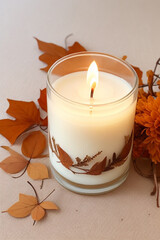Obraz na płótnie Canvas A vanilla-scented candle is being burned on a beige background, creating a cozy and warm autumn atmosphere with dried leaves and flowers. Generated with AI