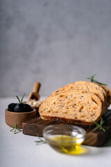 Homemade sourdough ciabatta slice bread with olives and rosemary on a white abstract table. Artisan bread
