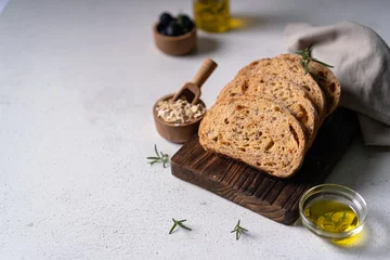 Fotobehang Homemade sourdough ciabatta slice bread with olives and rosemary on a white abstract table. Artisan bread © ILHAM_PS