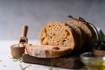 Homemade sourdough ciabatta slice bread with olives and rosemary on a white abstract table. Artisan bread