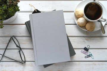 Blank book cover for mock up - flat lay with books, drink, plant and reading glasses.