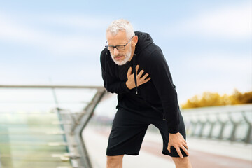 Elderly sportsman with heart pain touching chest, jogging outdoor