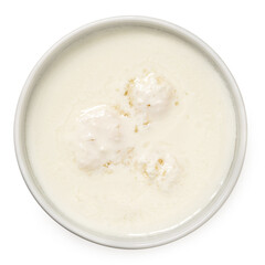 Milk with kefir grains in a white ceramic bowl isolated on white from above.