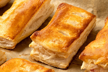 Savory filled puff pastries on baking paper. High angle.