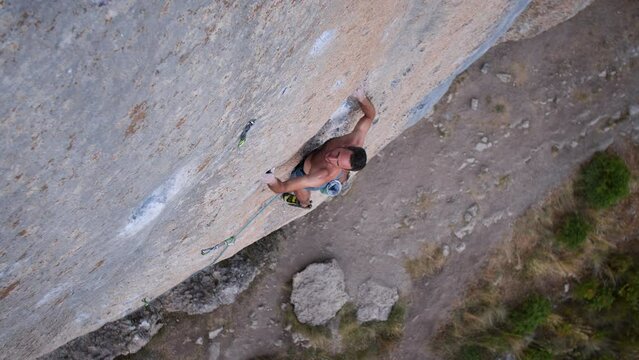 Young man lead climbing a hard and steep section of the wall in C&eacute;&uuml;se, France.
Following camera movement, low angle, 4K.