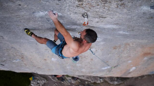 Young man lead climbing a hard and steep section of the wall in C&eacute;&uuml;se, France.
Following camera movement, low angle, 4K.