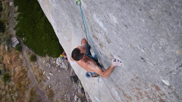 Young man lead climbing a hard and steep section of the wall in C&eacute;&uuml;se, France.
Following camera movement, low angle, 4K.