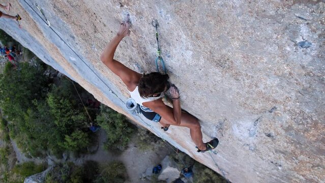 Young woman onsight lead climbing a hard and steep section of the wall in C&eacute;&uuml;se, France.
Following camera movement, low angle, 4K.