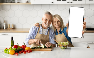 Delivery App. Happy Senior Couple Showing Blank Smartphone While Cooking In Kitchen
