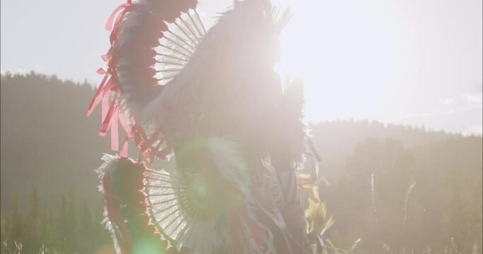 Beautiful Shot of Young Indigenous Boy Fancy Dancing In traditional Regalia at sunset on the prairies of Alberta Canada, Tsu'Tina Nation