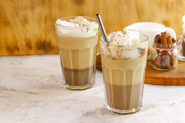 Coffee with whipped cream in a glass glass on a brown background