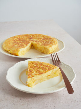 Spanish potato omelette with a triangle-shaped portion cut in a plate with fork