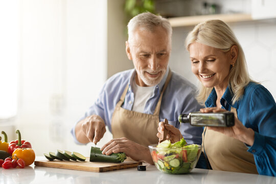 Happy Senior Couple Preparing Tasty Lunch Together In Kitchen,