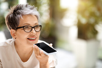 Closeup of mature businesswoman recording voice mail on smartphone