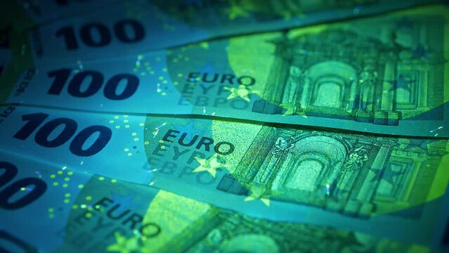 Euro banknotes under ultraviolet light. Security signs and elements on real 100 euro banknotes glow under UV light. Checking banknotes for authenticity. Protection against counterfeiters