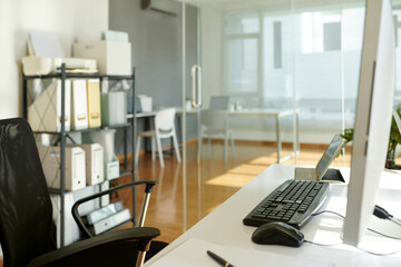 Empty chair next to computer desk in office of modern company