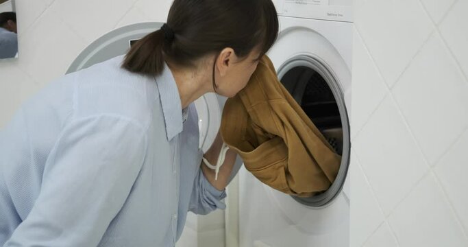 In a state of disappointment, a woman expresses her dissatisfaction with the outcome of her laundry in the washing machine. Her downcast expression reflects her frustration with the cleaning process.