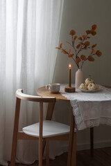 Cozy autumn home. Autumn decor, candle on a round wooden table in the living room
