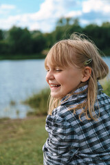 A girl of 10-12 years old sincerely laughs and enjoys life while relaxing in nature. The child experiences positive emotions.