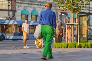 A dandy man walks along a city street. Fashionably dressed adult man rushing to a date.
